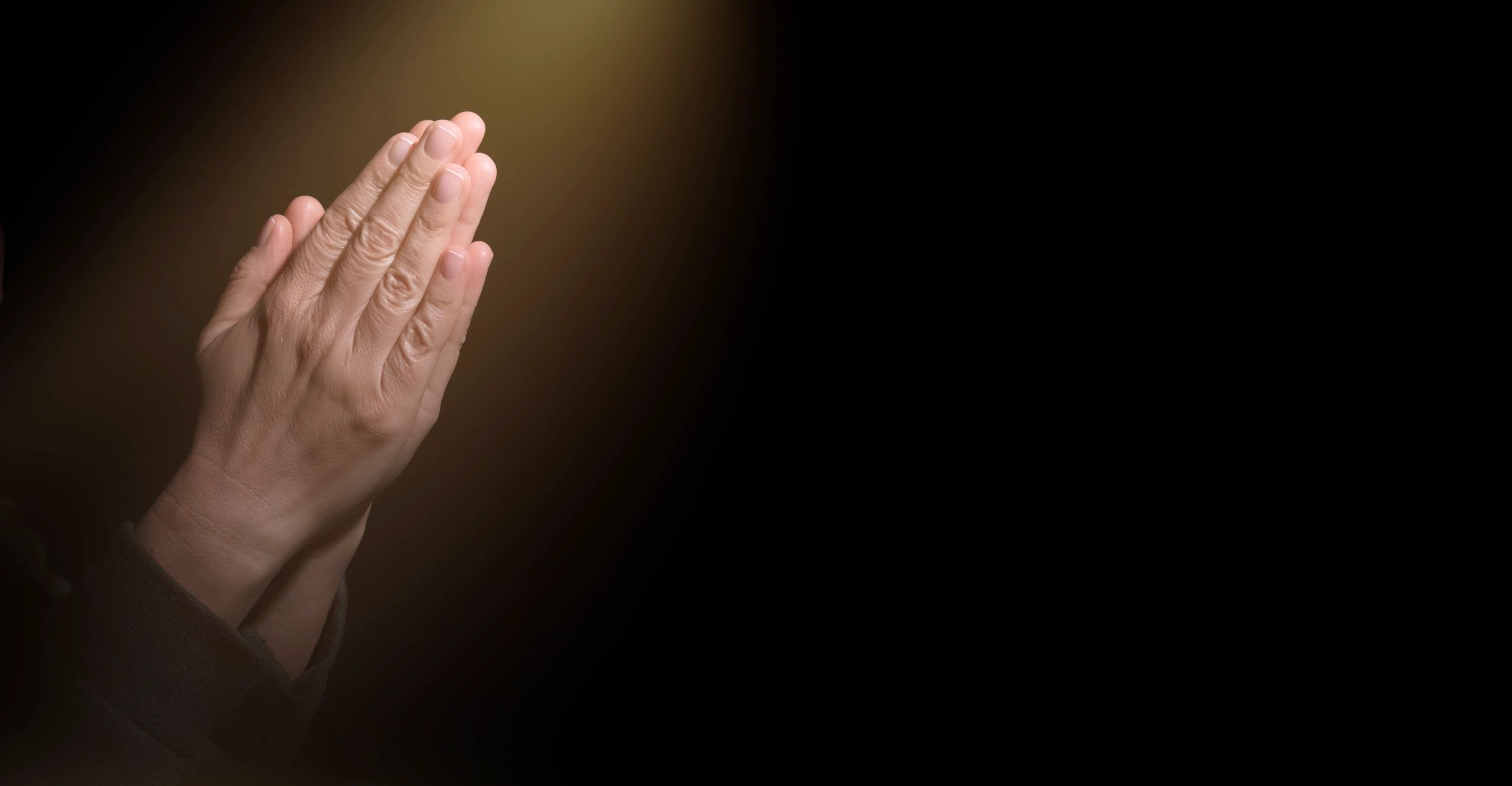 Hands together in prayer with light beam