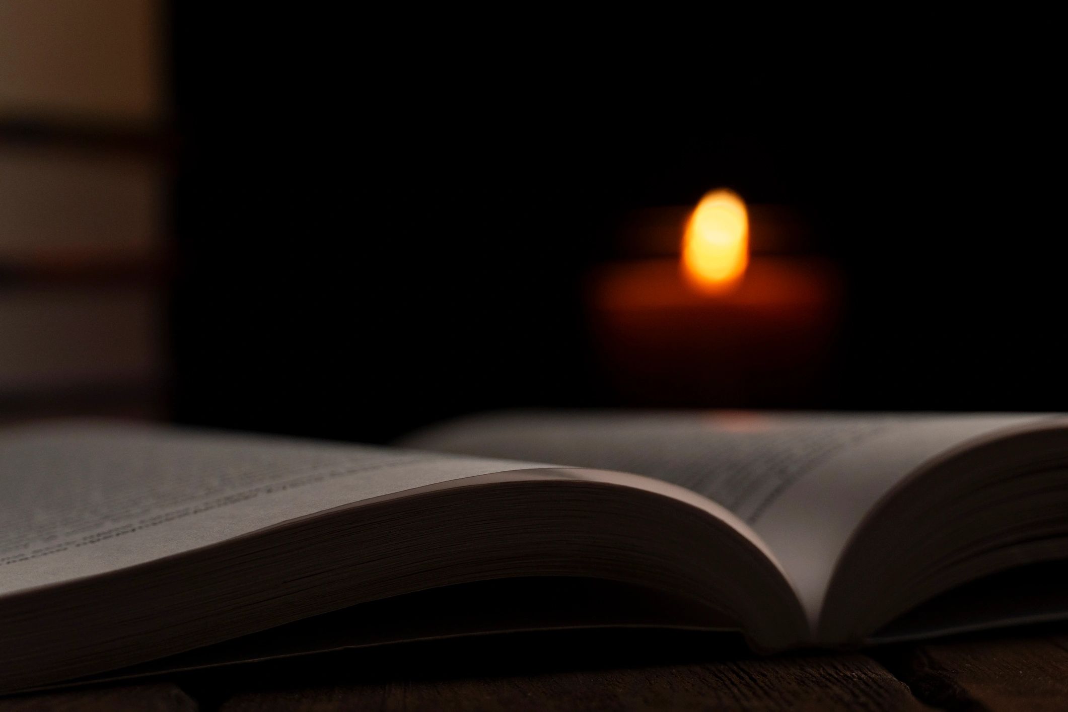 Open book with candlelight in a cozy dark setting