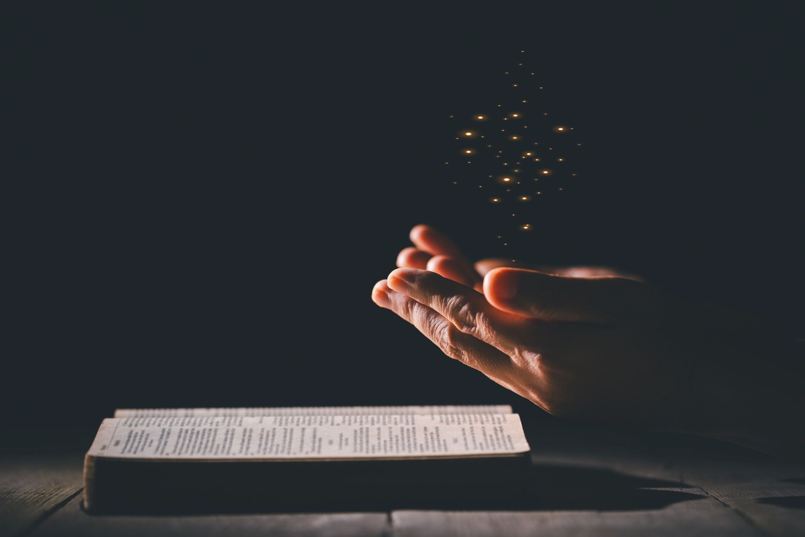 Hands clasped in prayer over a Bible