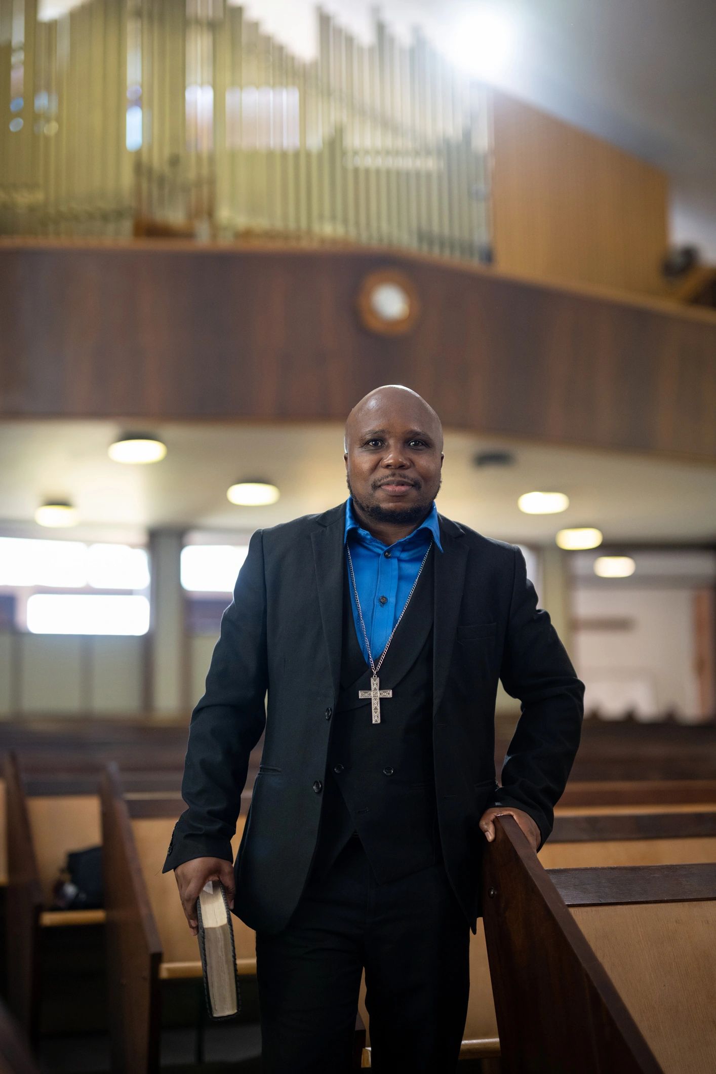 Portrait pastor standing in church holding his bible